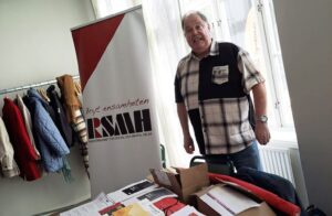 Stefan Wallerek i rutig skjorta vid bord med RSMH-broschyrer